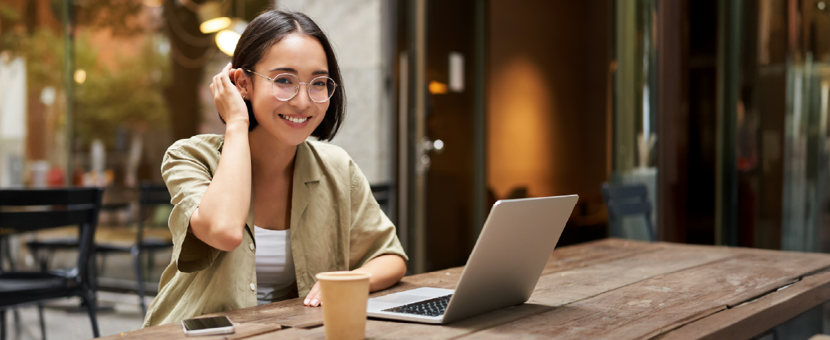 Mulher oriental de cabelos curtos trabalhando em seu laptop em um café