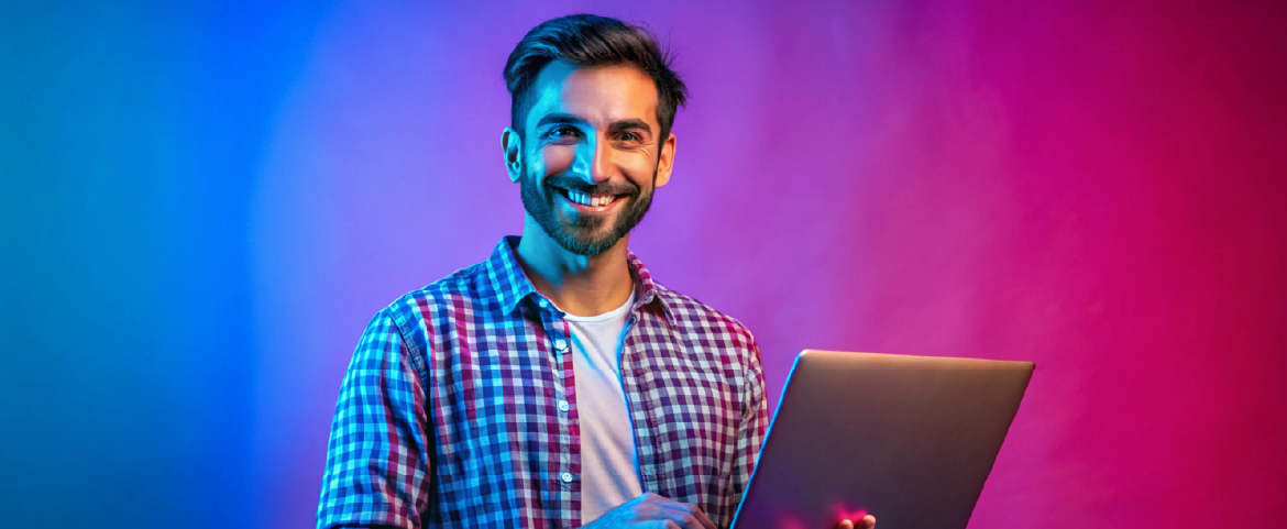 Homem de camisa xadrez, sorrindo segurando um laptop
