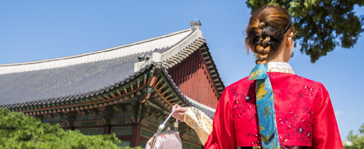 Mulher coreana de costas com roupas típicas de frente a um templo