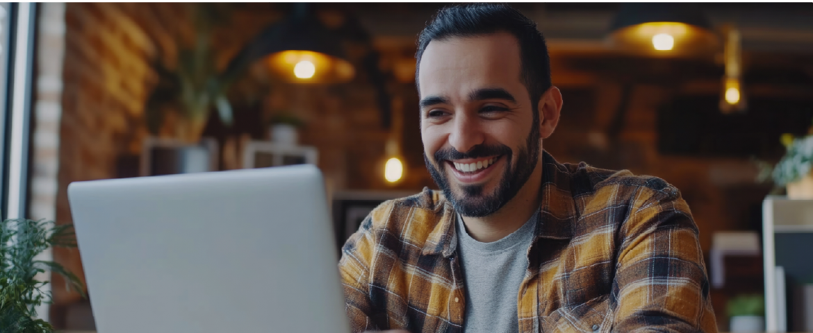 Homem feliz, usando camisa xadrez trabalhando no laptop Homem feliz, usando camisa xadrez trabalhando no laptop