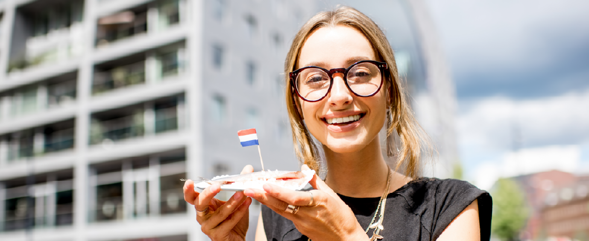 Mulher sorrindo com pedaço de torta na mão com ma pequena bandeira de Luxemburgo.
