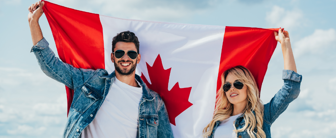 Casal de óculos escuros segurando uma bandeira do Canadá.
