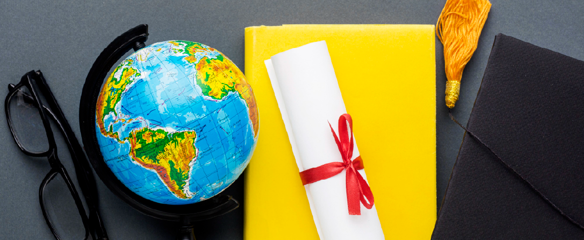 Composição de objetos: óculos de grau, globo terrestre, diploma, capelo e livro.