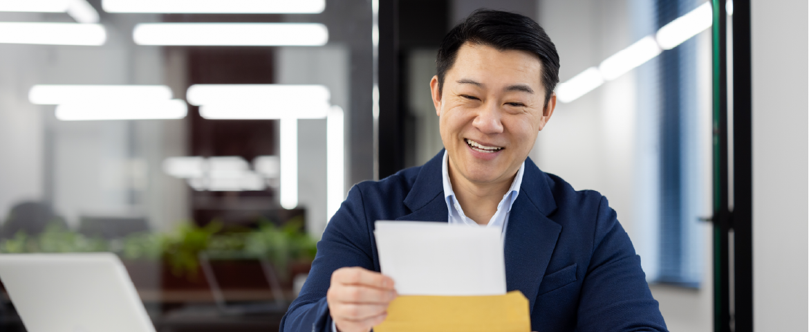 Homem oriental sorrindo e segurando um documento nas mãos. Homem oriental sorrindo e segurando um documento nas mãos.