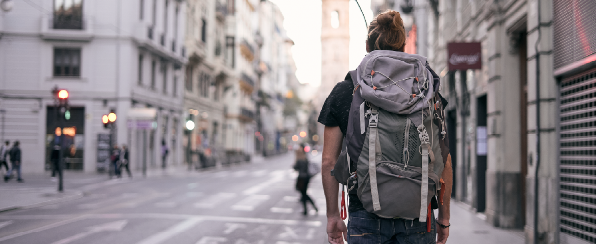 Homem com mochila nas costas passeando pelas ruas.