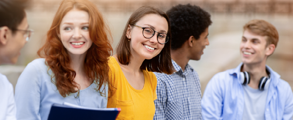 Grupo de estudantes alegres em ambiente externo de Universidade.
