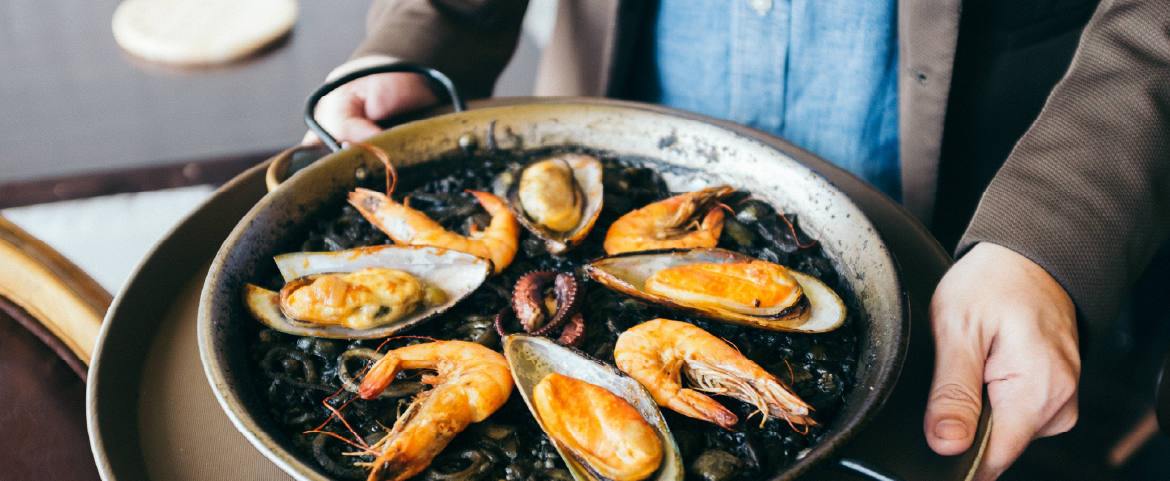 Homem servindo um prato típico da Espanha.