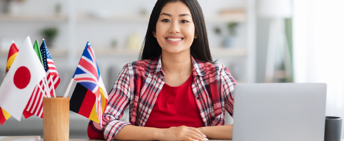 Mulher oriental Mulher oriental em ambiente de trabalho com laptop e bandeiras de vários países